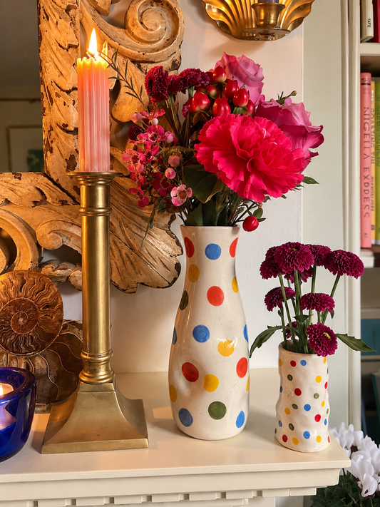 The Itsy-Bitsy Vase filled with pink and red flowers beside the matching candle holder on a mantelpiece
